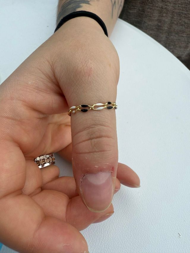 Hand wearing a delicate gold-and-black chain bracelet against a white background