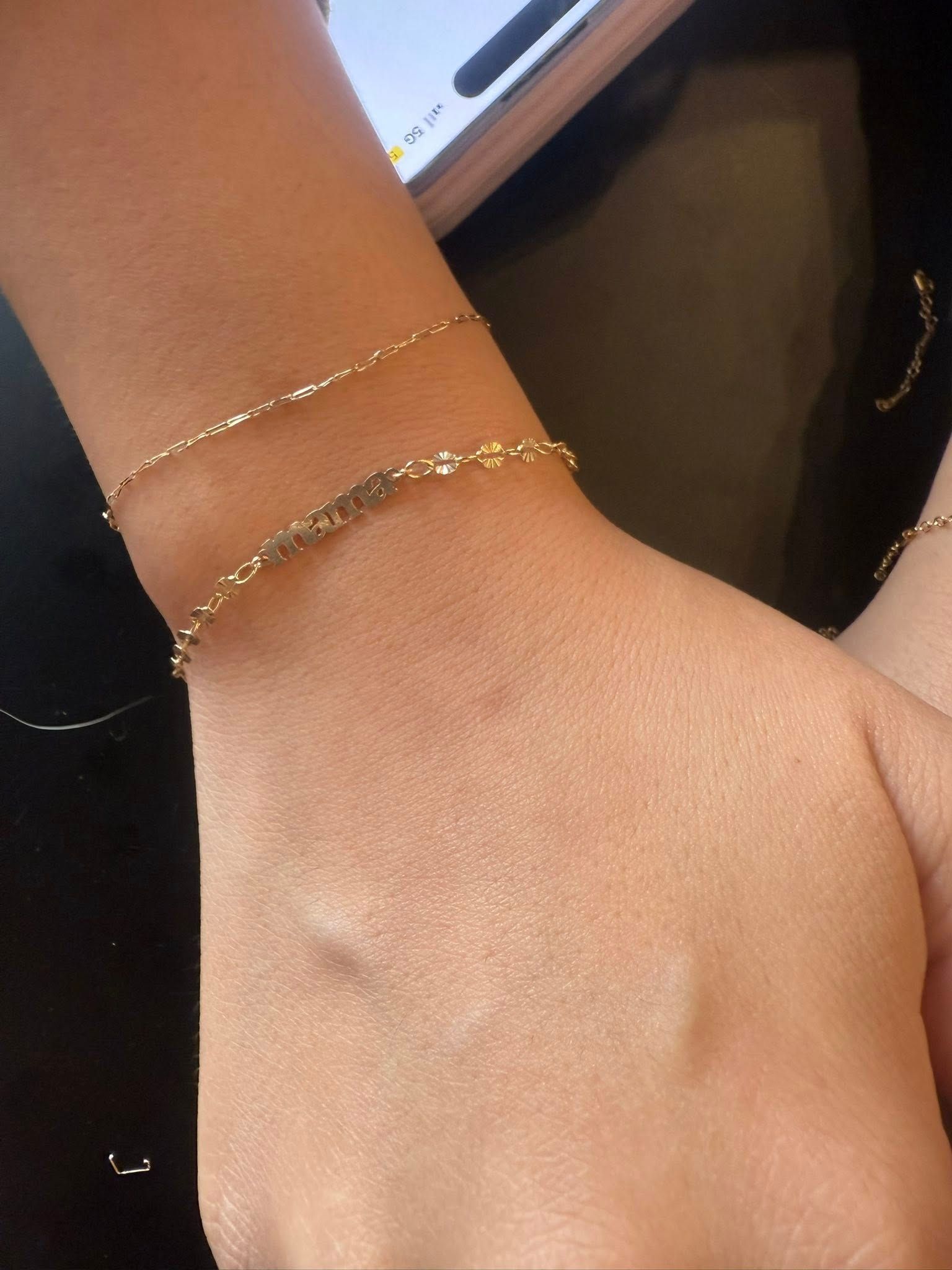 Close-up of a wrist wearing a delicate gold bracelet against a dark background