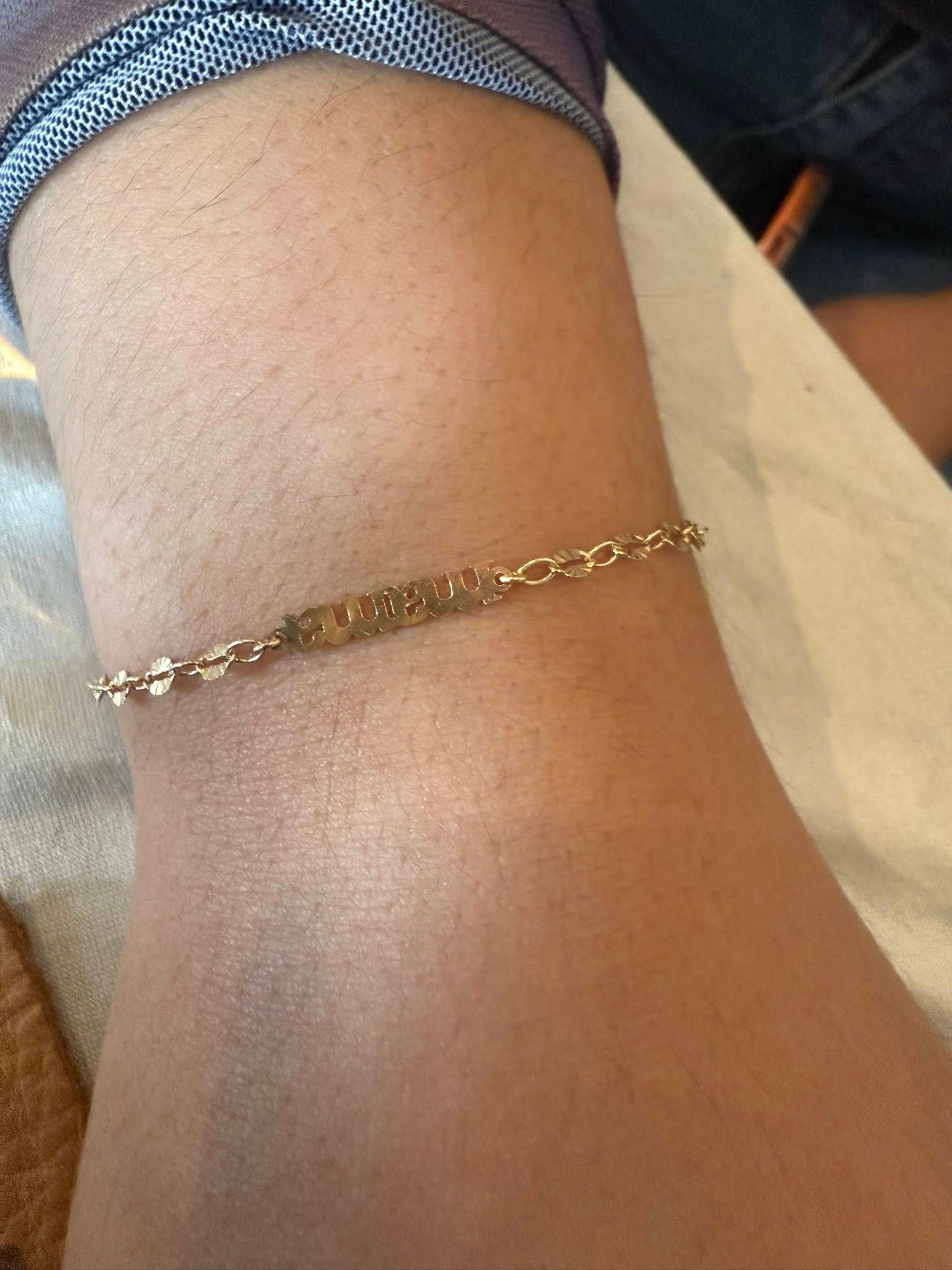 Close-up of a wrist wearing a thin gold bracelet against light skin.