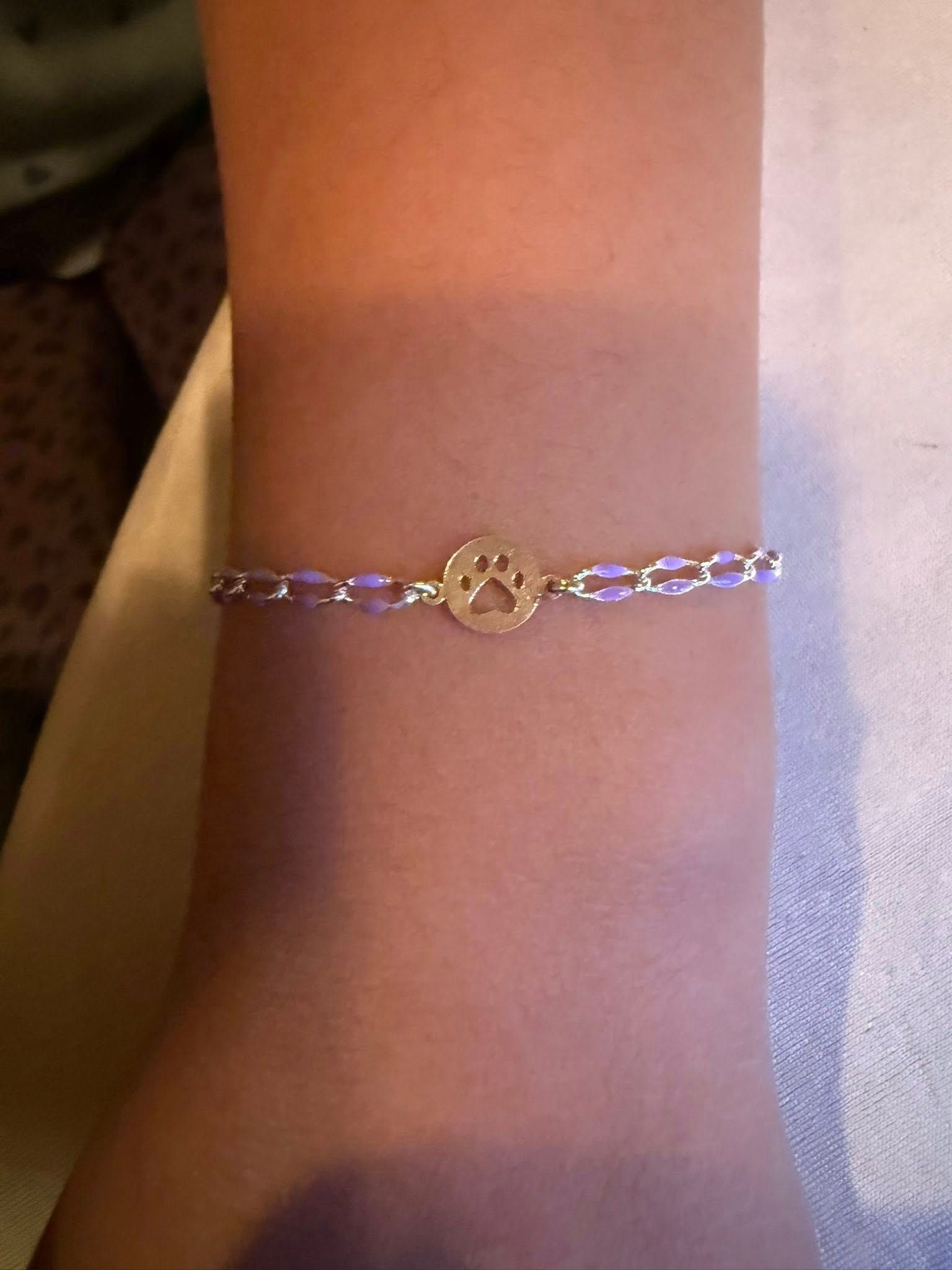 Close-up of a silver bracelet with a gold center charm on a wrist