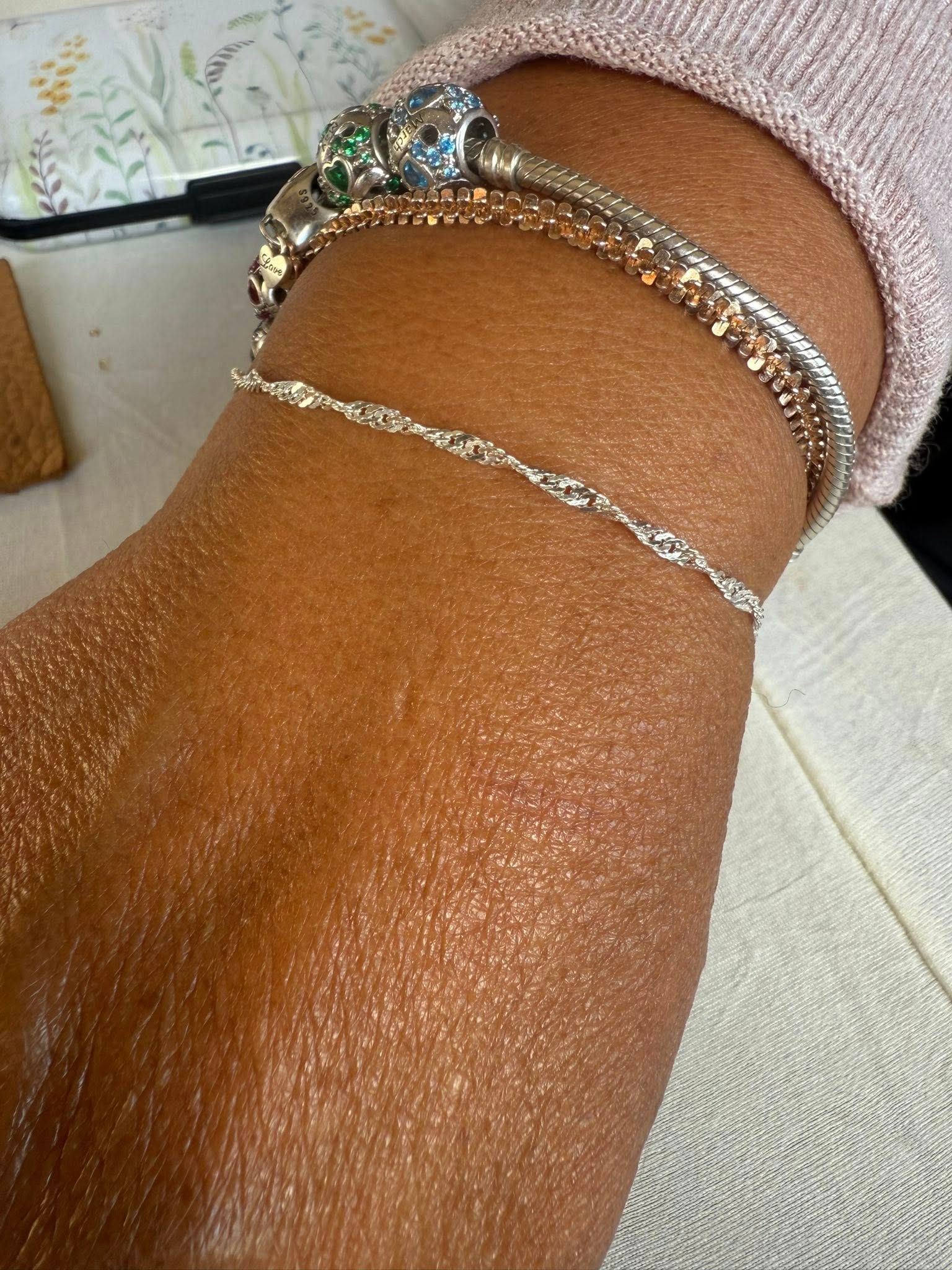 Close-up of an arm wearing silver bracelets and a pink beaded scrunchie.