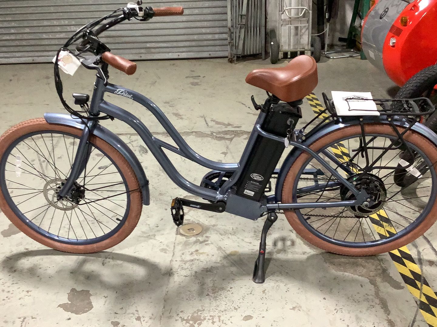 An electric bike is parked in a garage next to a red car.