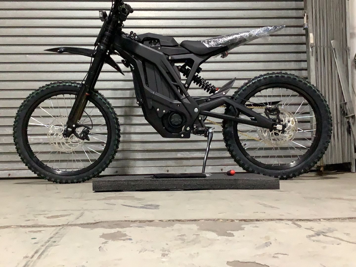 A black dirt bike is parked in front of a garage door.