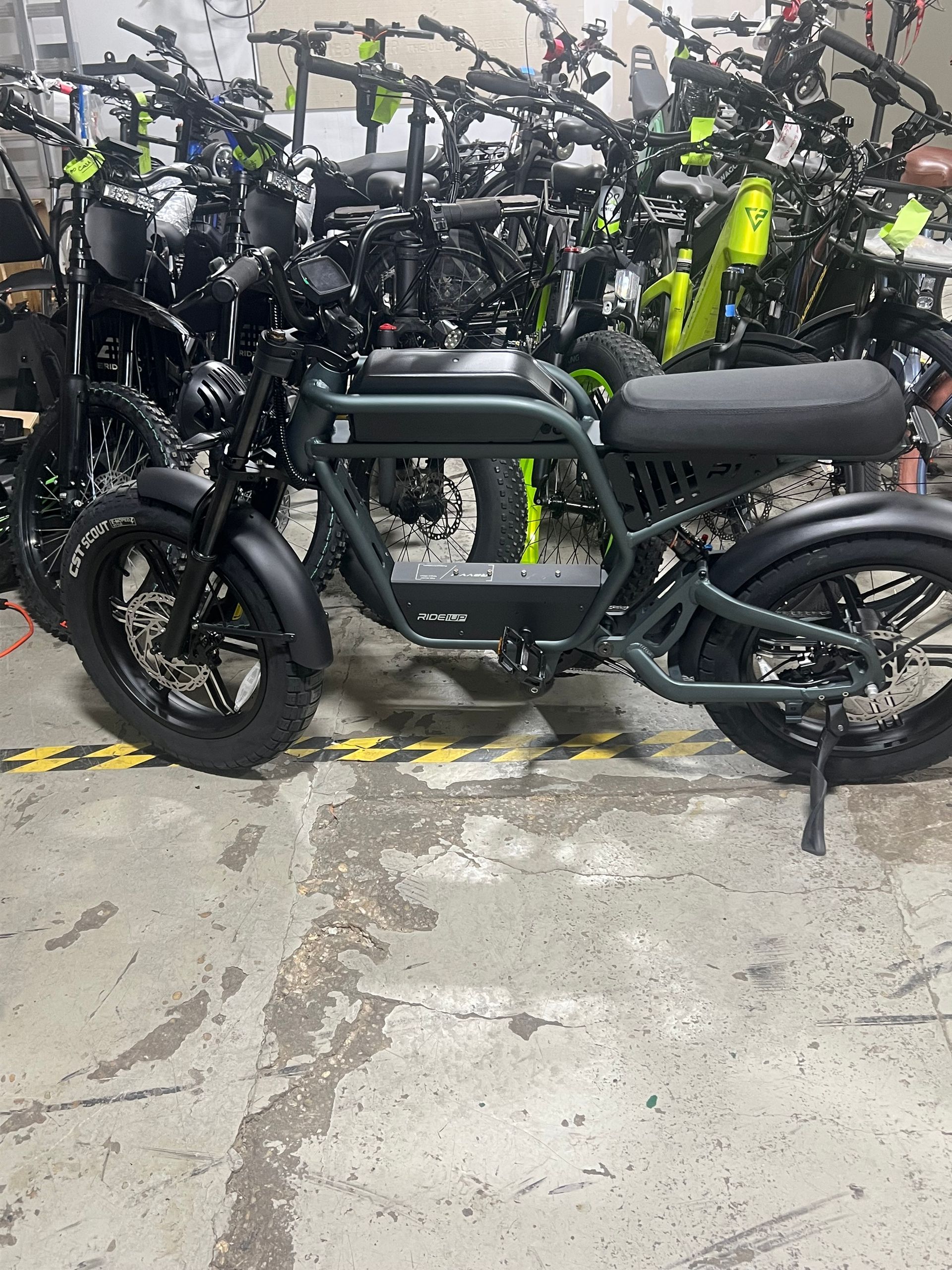 A motorcycle is parked in a garage next to a bunch of other motorcycles.