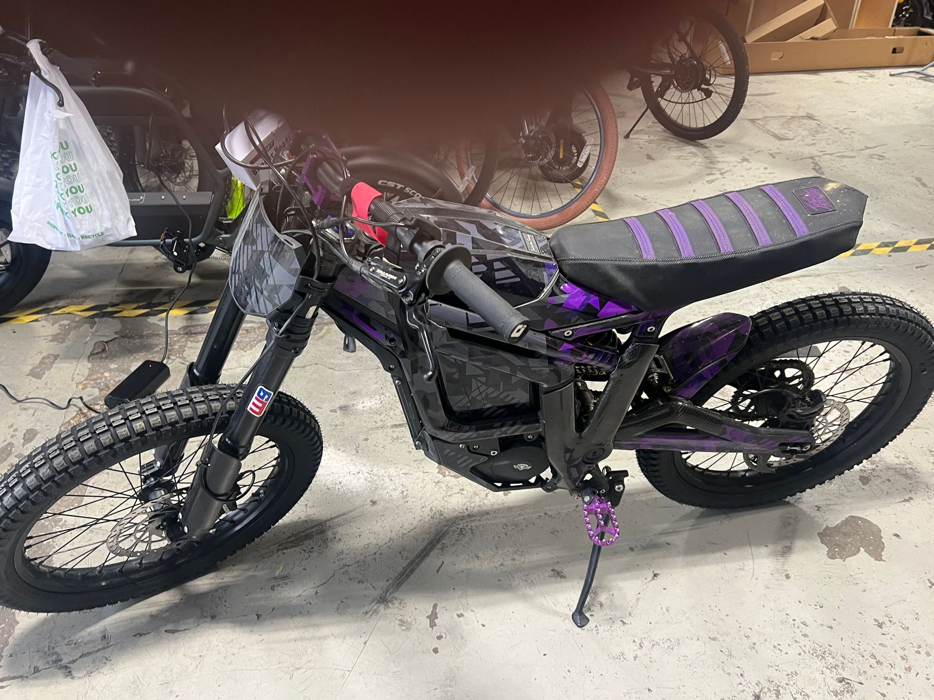 A black and purple dirt bike is parked in a garage.