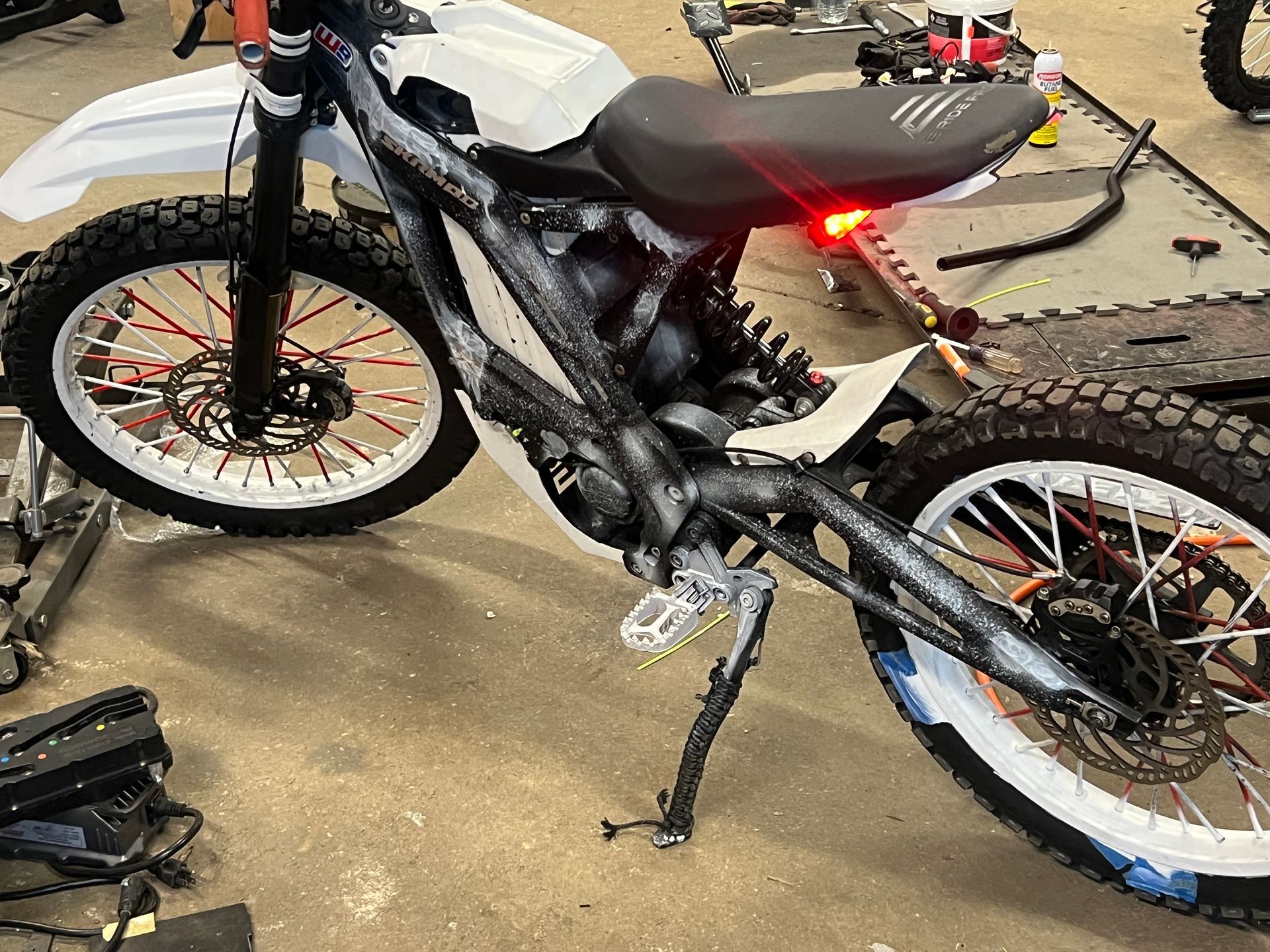 An electric dirt bike is sitting on the floor in a garage.