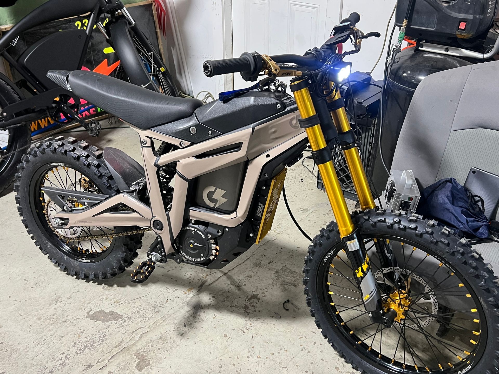 A black and gold dirt bike is parked in a garage.