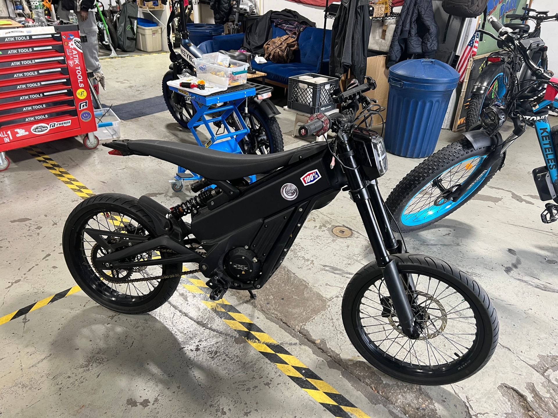 A black electric dirt bike is parked in a garage.