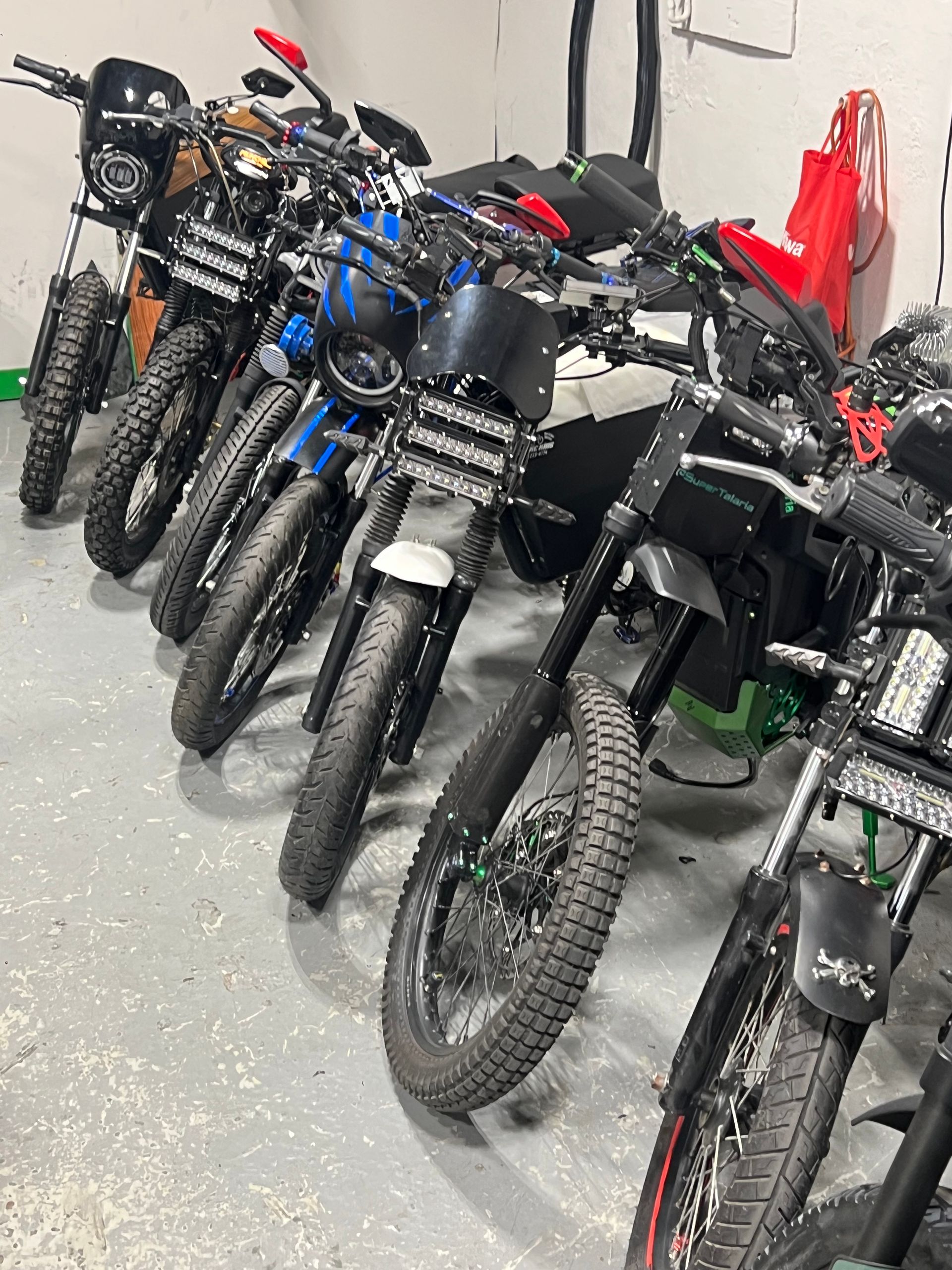 A row of motorcycles are parked in a garage.