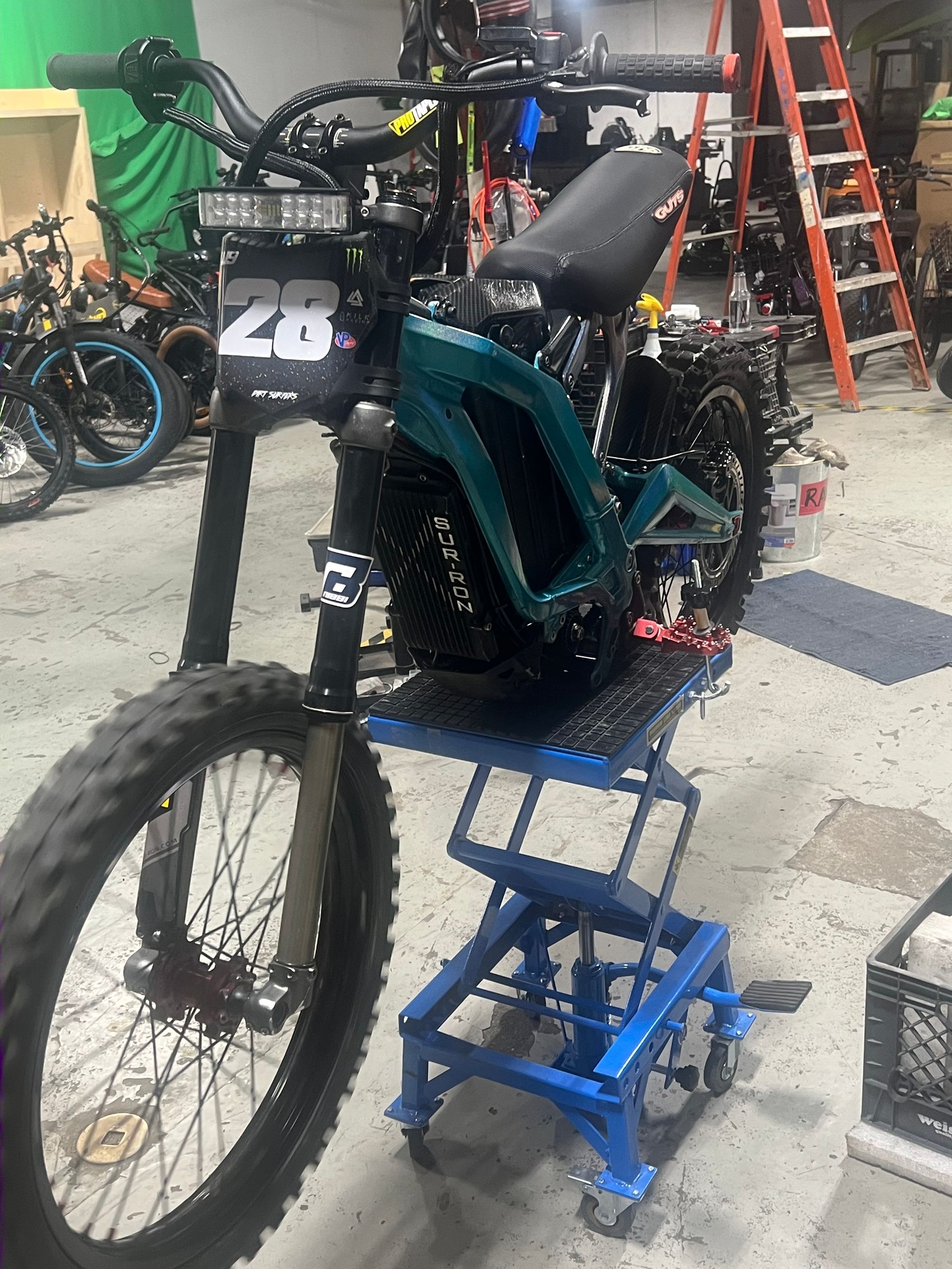 A motorcycle is sitting on top of a blue lift in a garage.