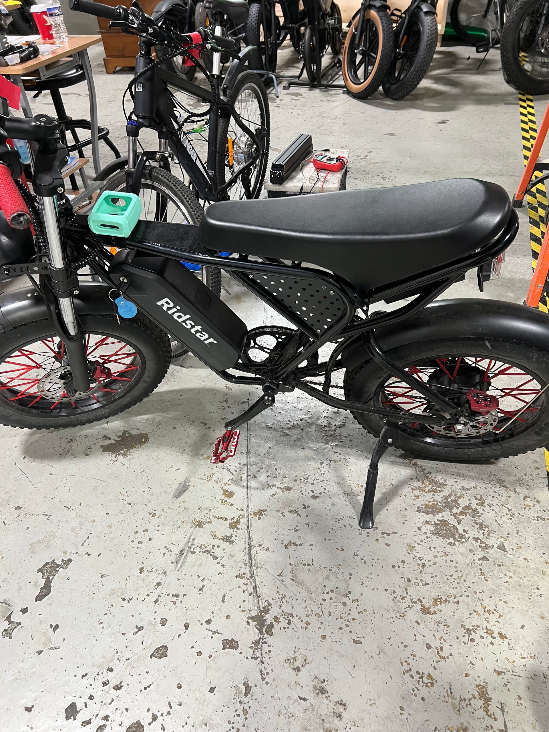 A black electric motorcycle is parked on the floor in a garage.