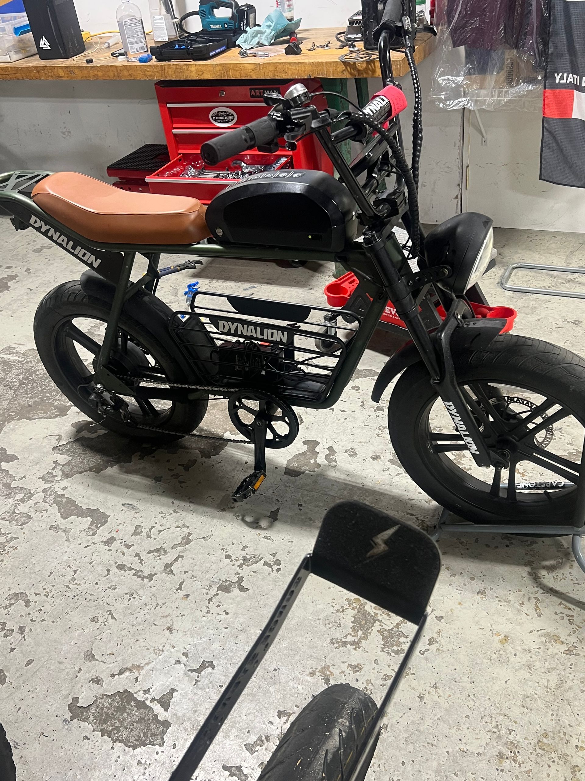 A motorcycle is parked in a garage next to a scooter.