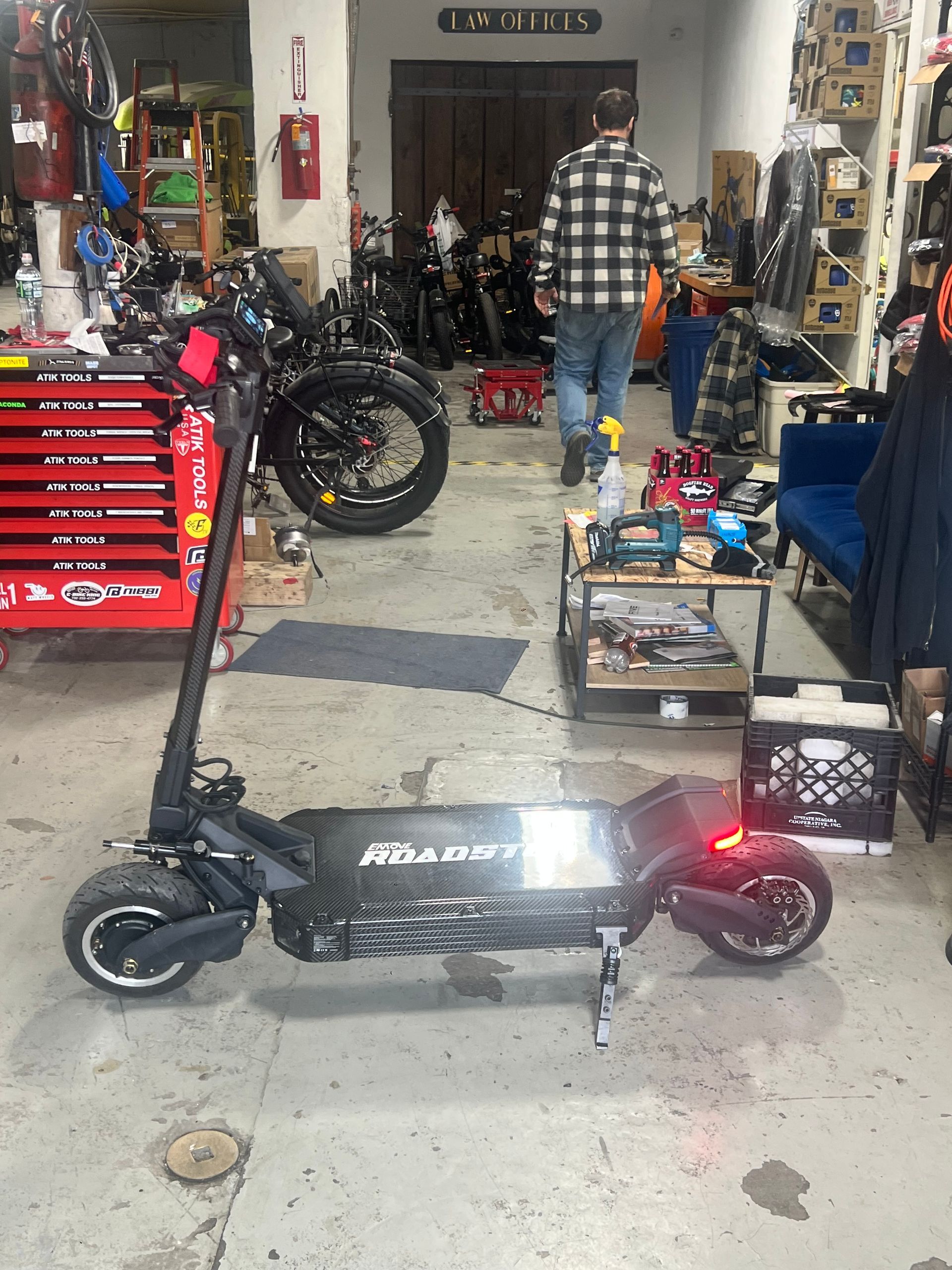 A man is standing next to a scooter in a garage.