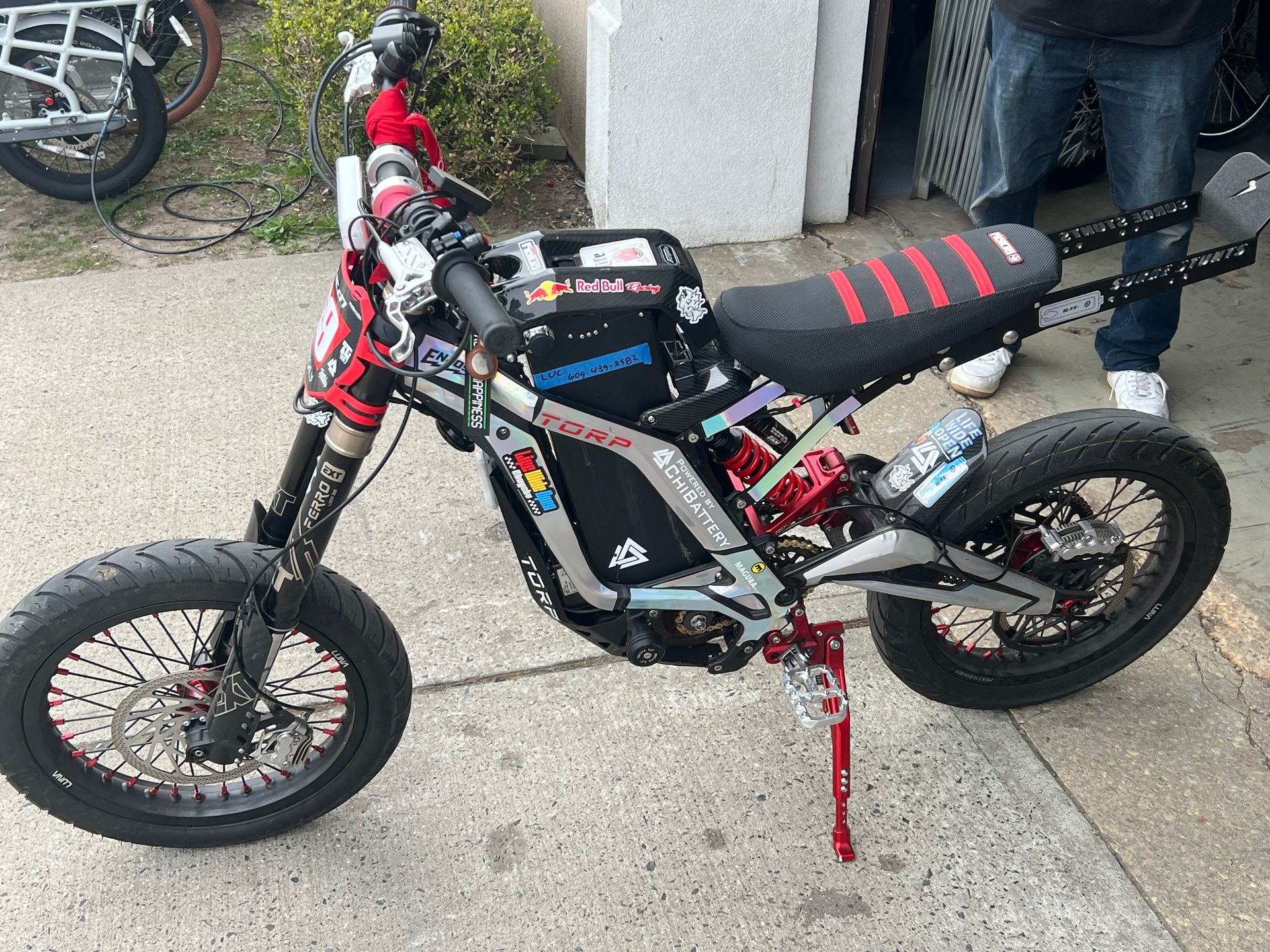 A man is standing next to a motorcycle parked on the sidewalk.