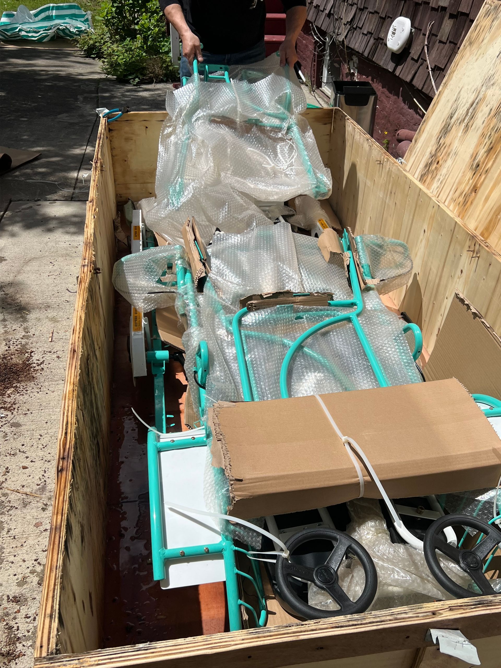 A person is loading a bicycle into a wooden box