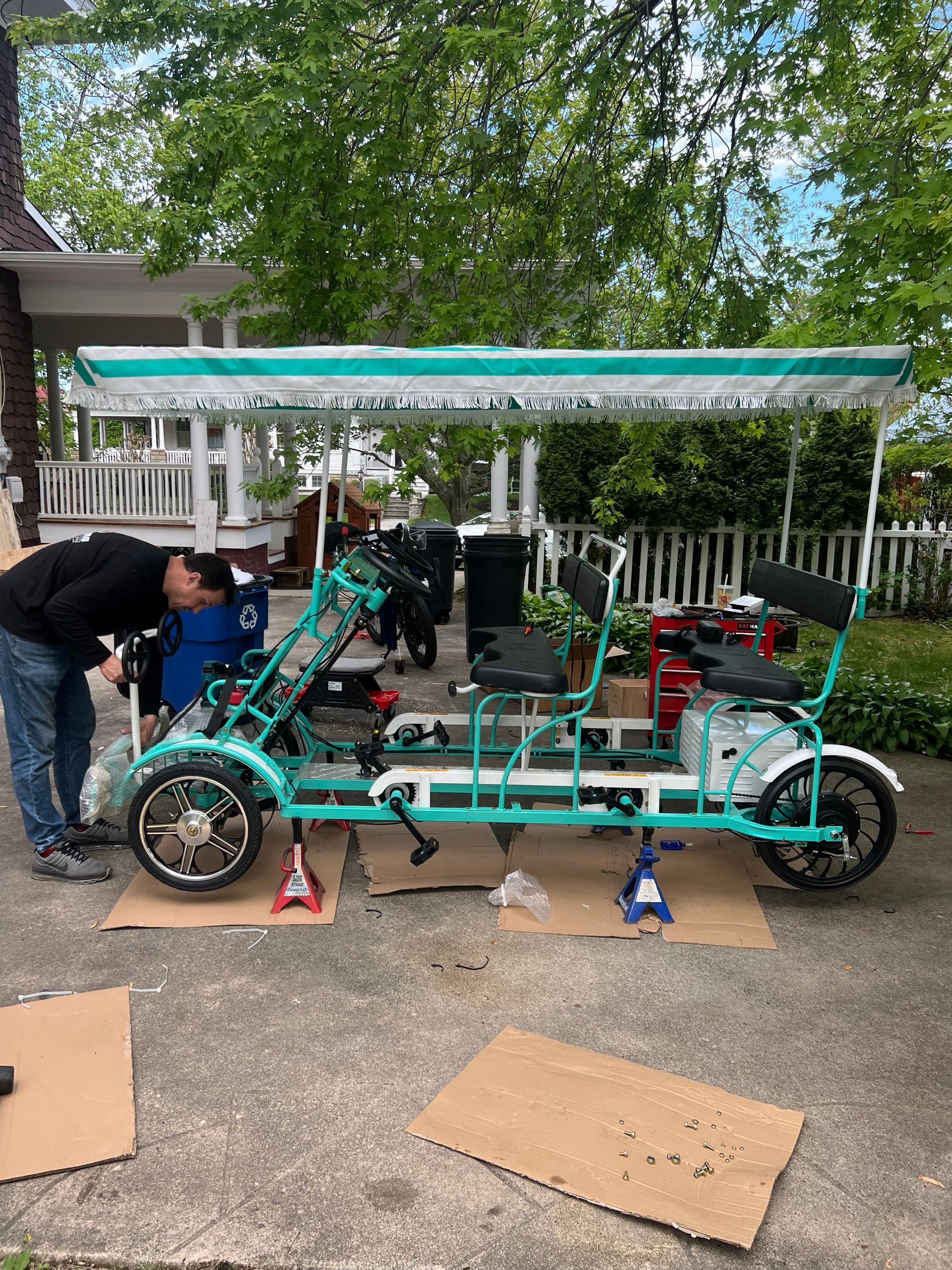A man is working on a green bicycle in a driveway.