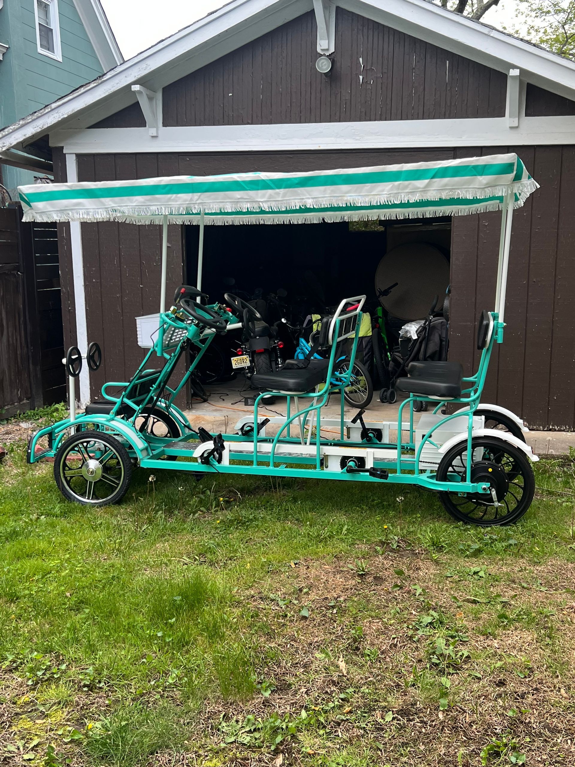 A green pedal bicycle with a canopy is parked in front of a garage.
