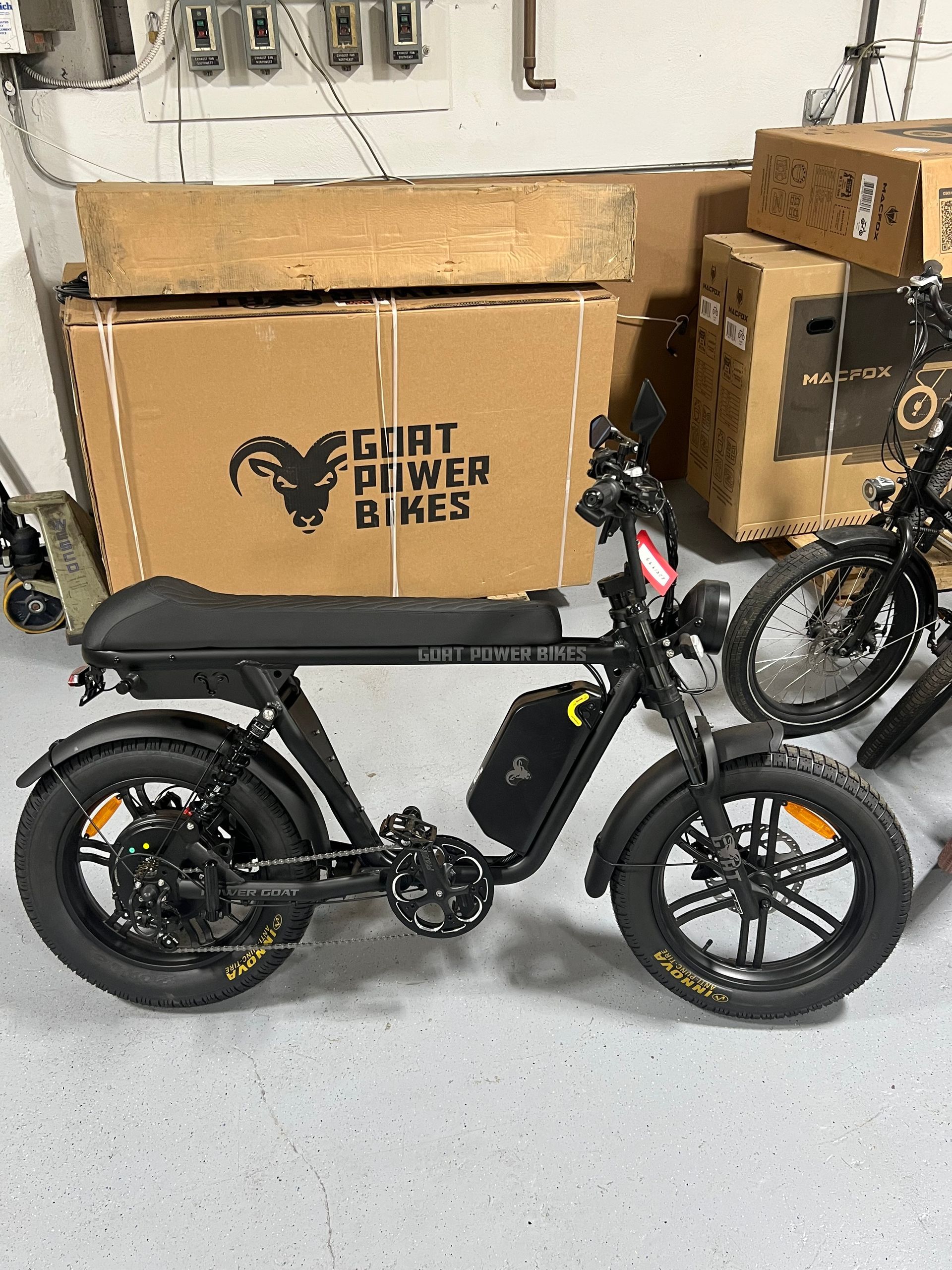 A goat power bike is sitting in front of a cardboard box.