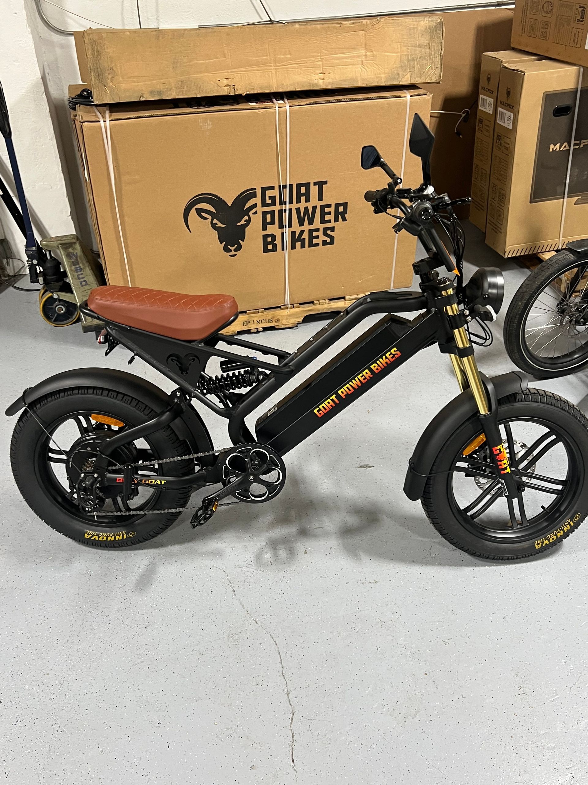 A goat power bike is parked in a garage next to a cardboard box.