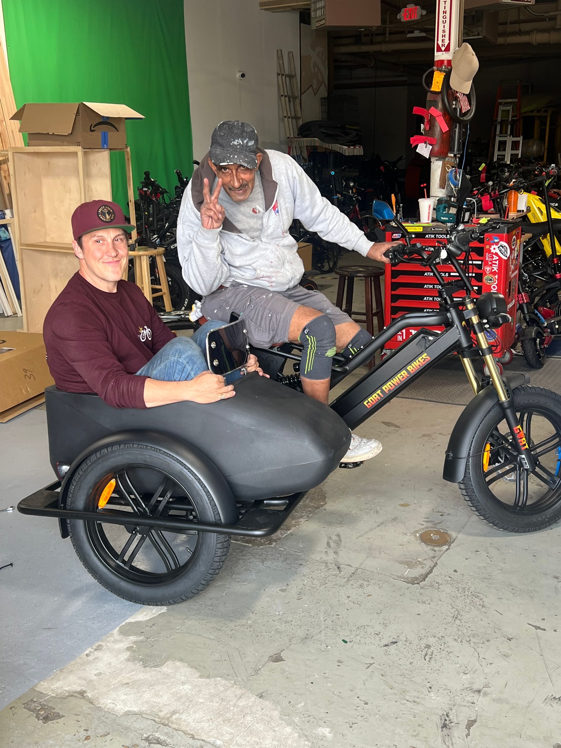 Two men are sitting on a sidecar motorcycle in a garage.