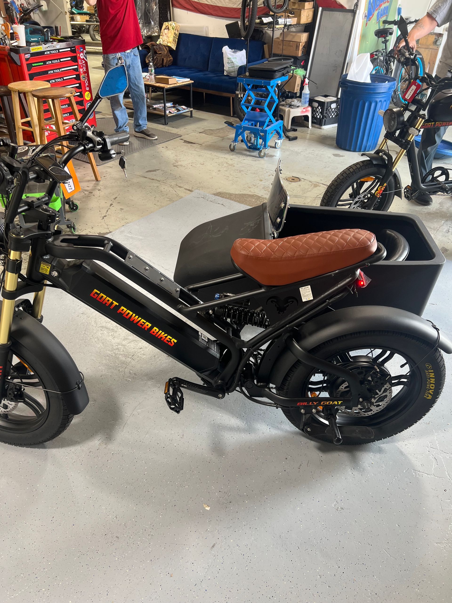 A black motorcycle with a brown seat is parked in a garage.