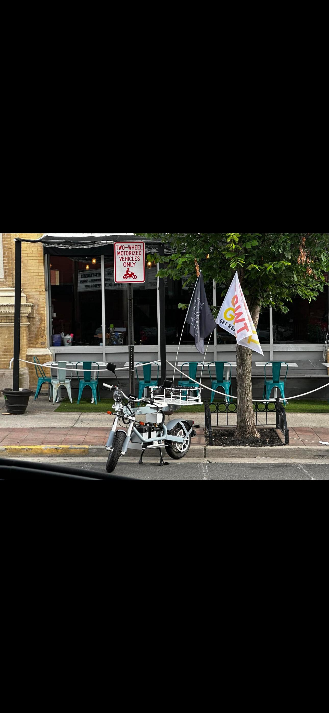 A motorcycle is parked on the side of the road in front of a restaurant.
