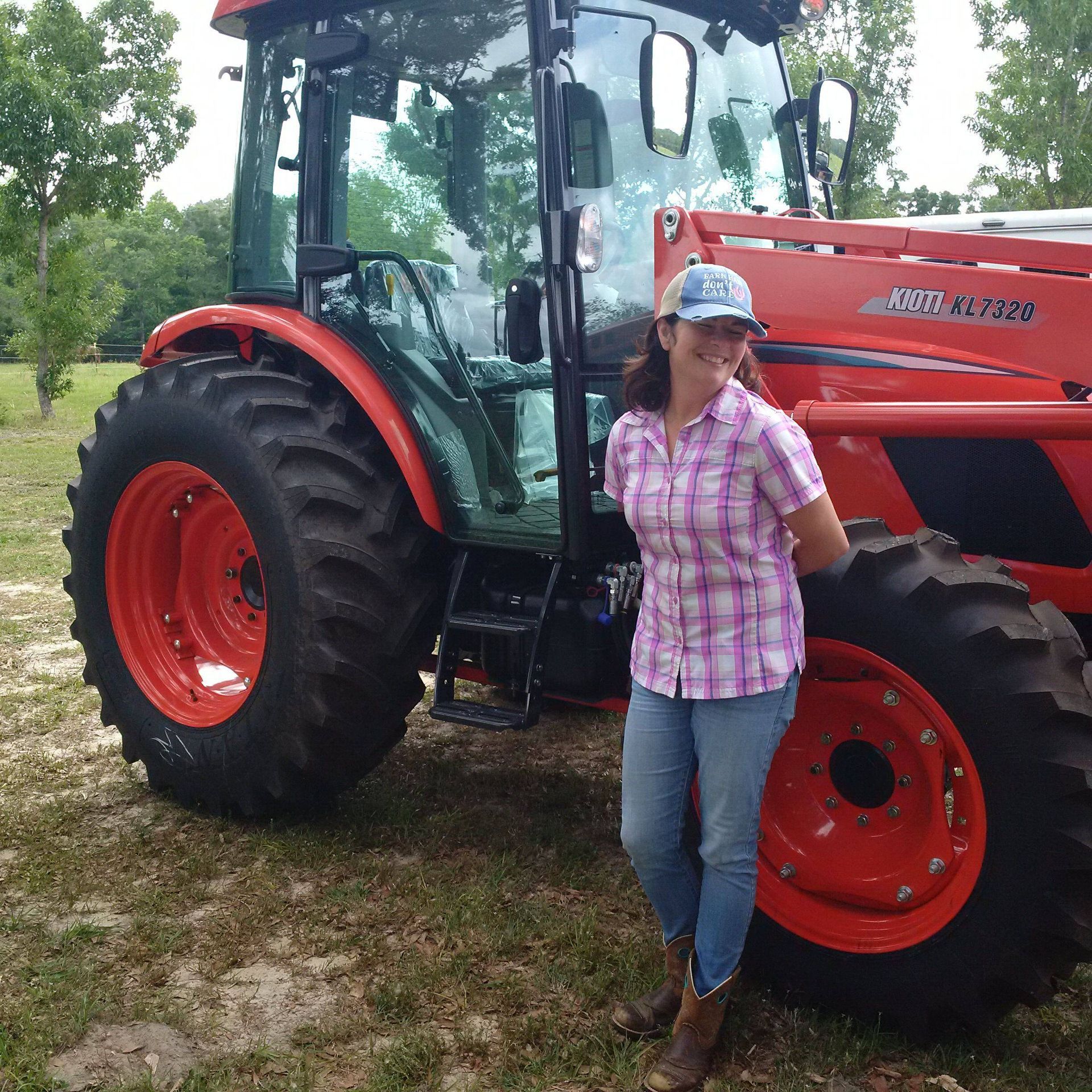 Person standing beside a red tractor in a rural setting