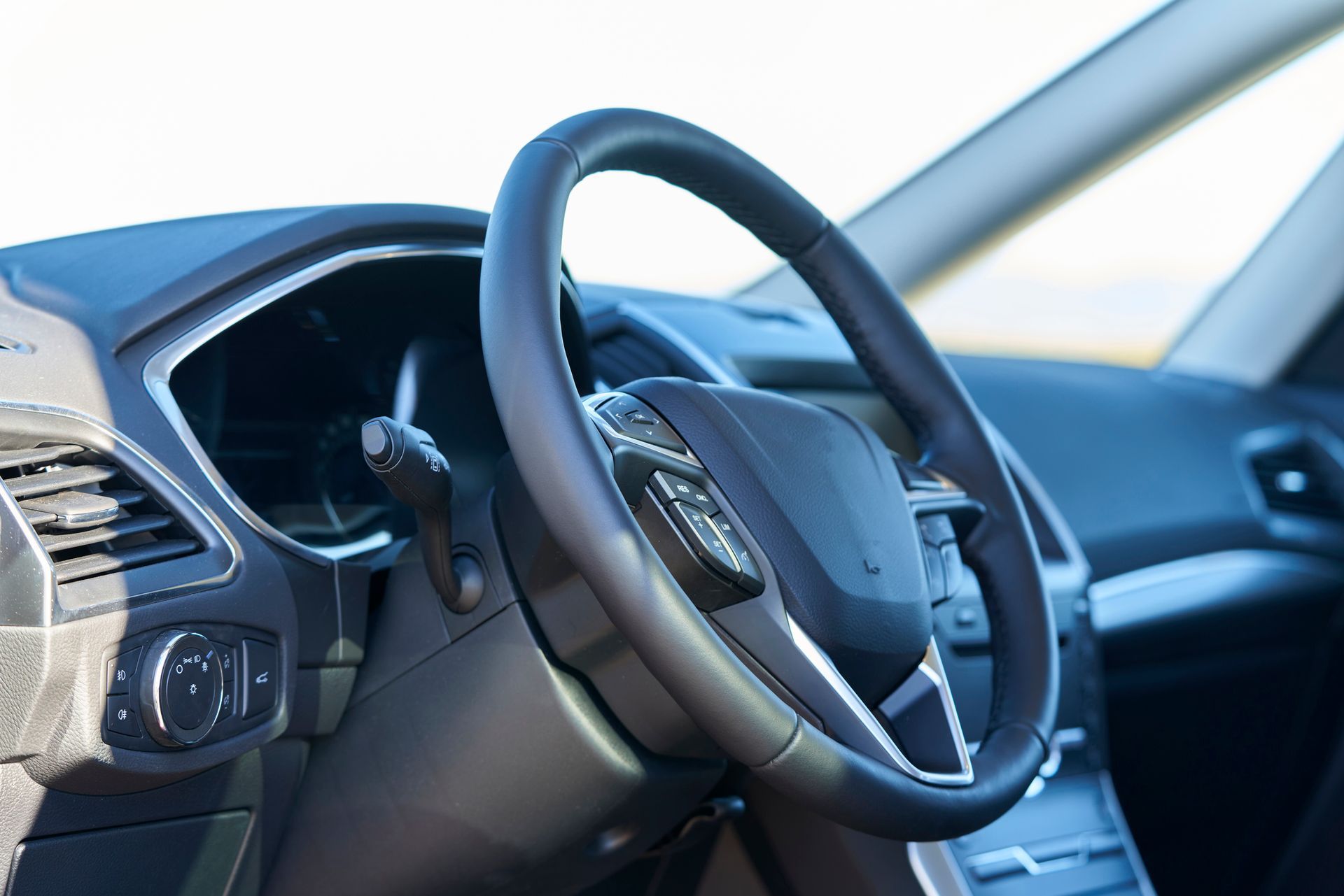 Black steering wheel inside a car, angled view of the dashboard and part of the windshield.