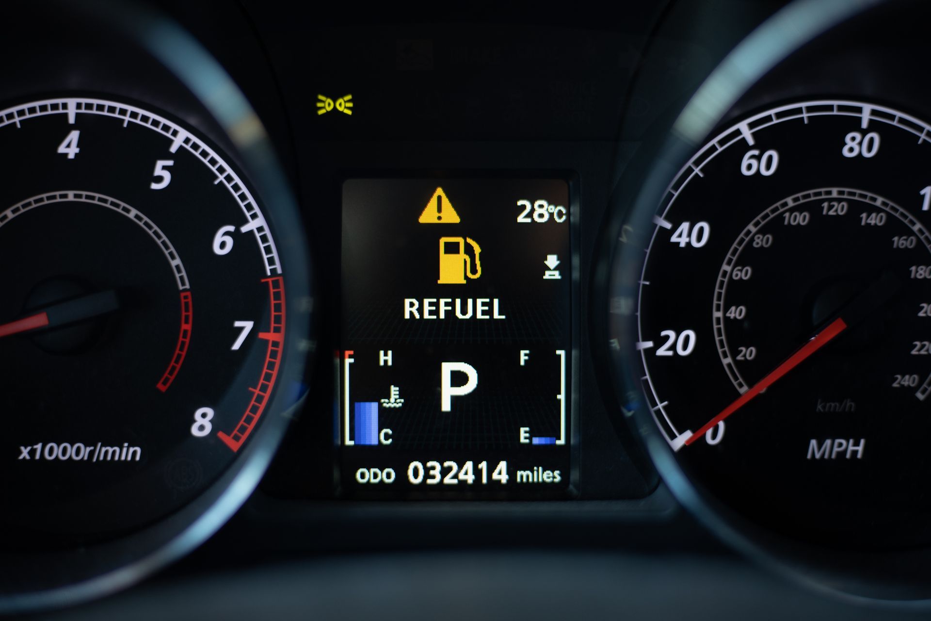 Car dashboard with warning lights, including 'REFUEL' and low fuel indicator. Odometer reads 032414 miles.