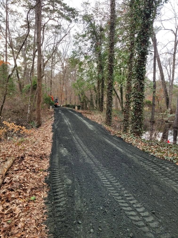 A gravel path through a wooded area with fallen leaves and bare trees in early spring.