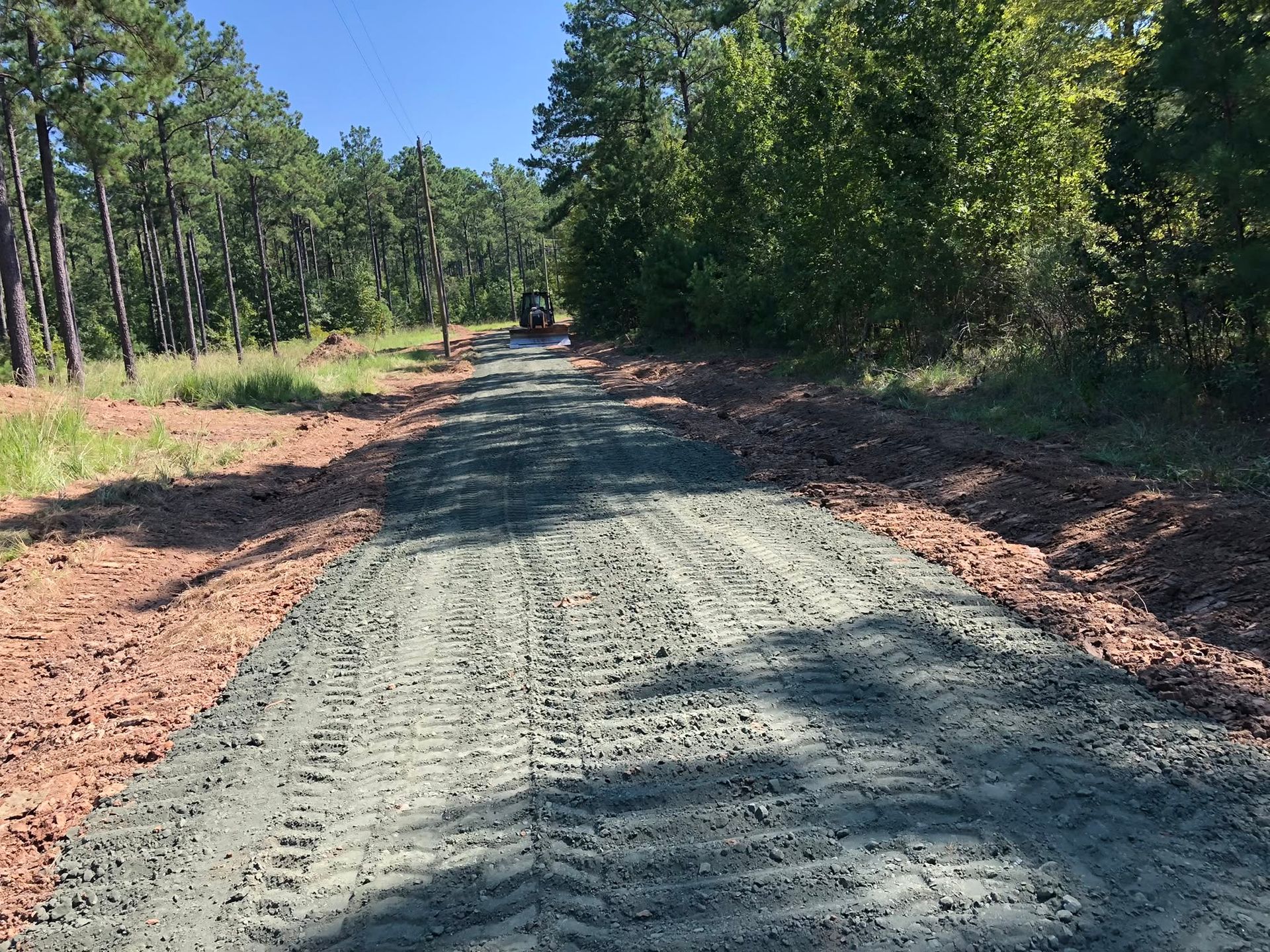 Fresh gravel road through a wooded area under bright sunlight