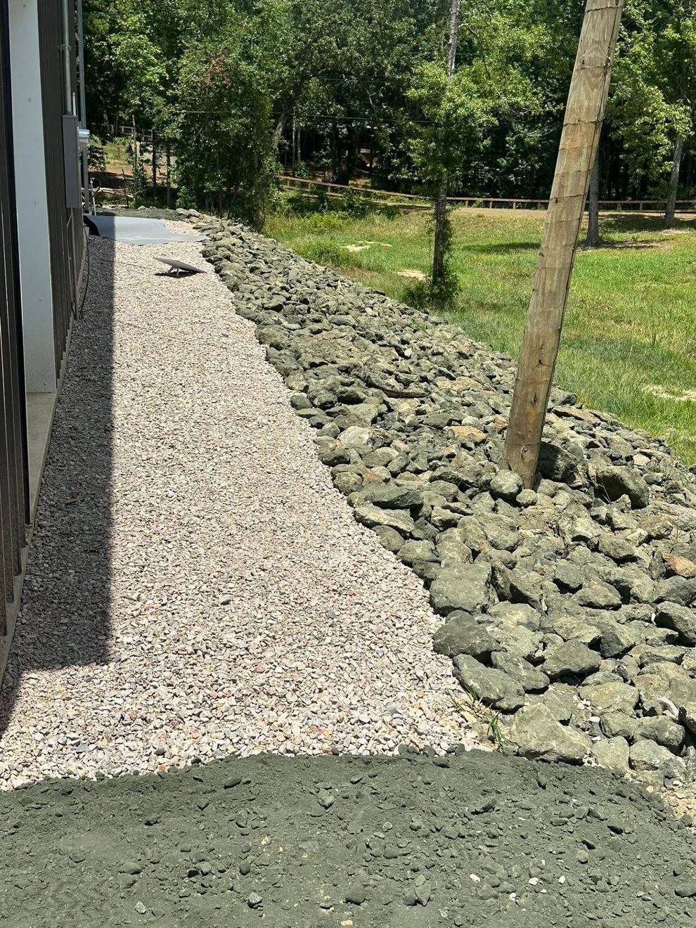 Gravel path beside a rocky border and young trees in a green landscaped area