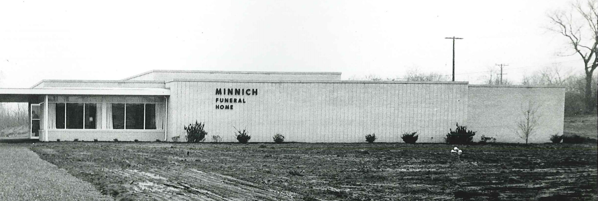 A low, one-story building with a flat roof, large windows, and a manicured lawn.