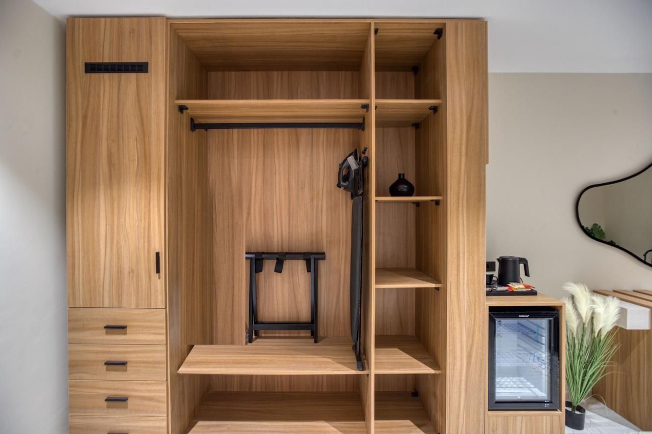 A hotel room with a large wooden wardrobe and a fridge.