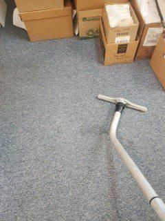 Vacuum hose on blue carpet beside stacked cardboard boxes in a storage area
