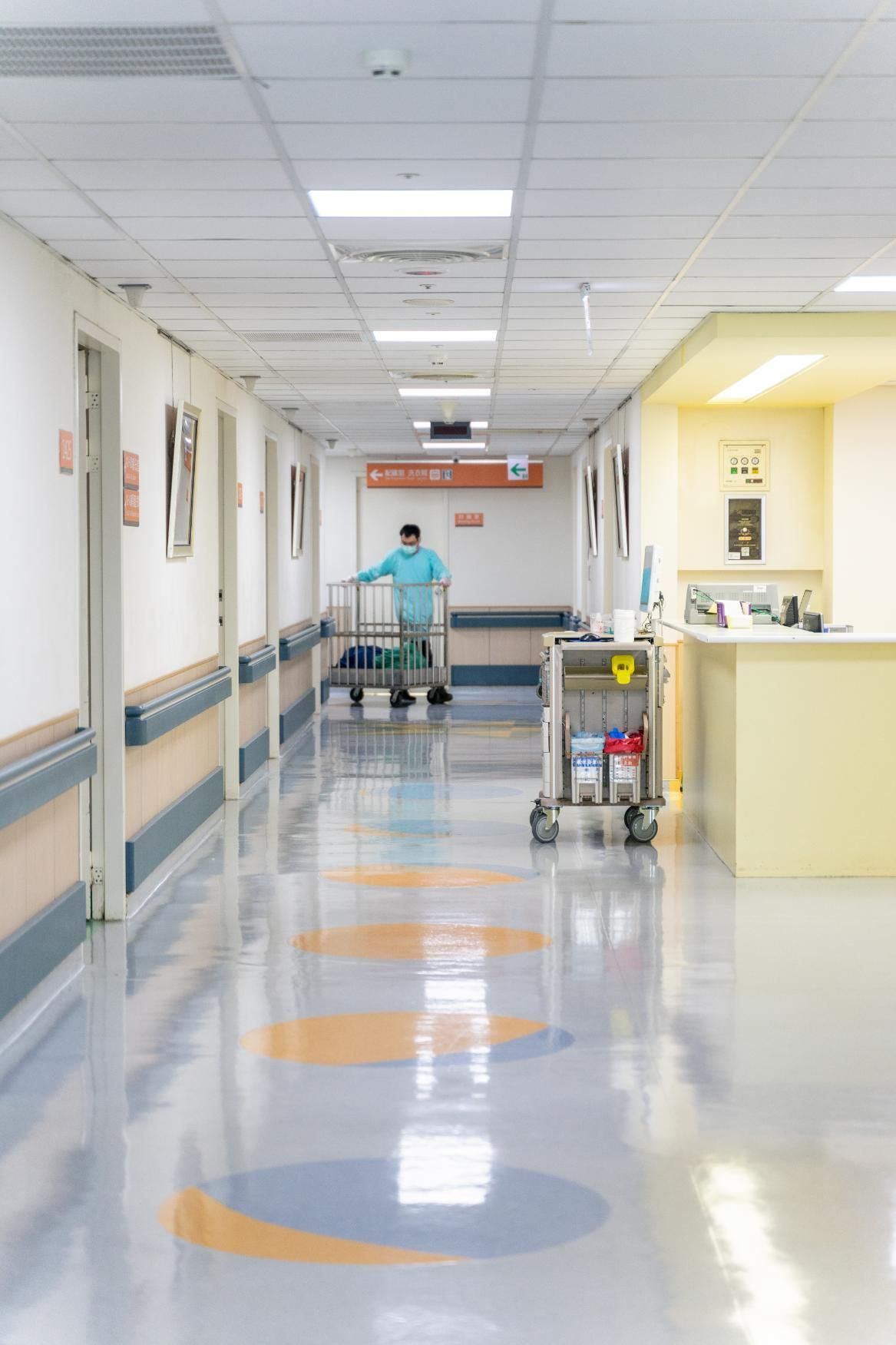 Empty hospital hallway with a person pushing a cart in the distance