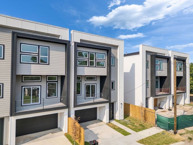 Modern gray duplex homes with garages and balconies in a new residential development