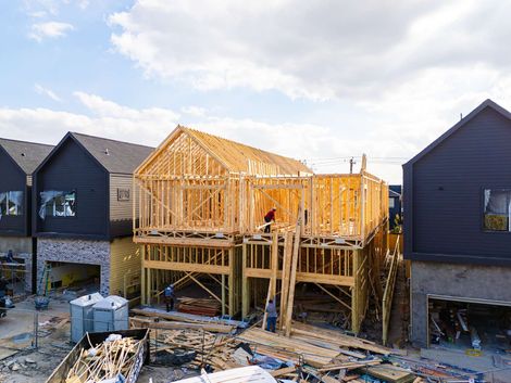 House under construction with exposed wooden framing between finished homes