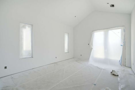 Empty white room under renovation with covered windows and plastic sheeting over a doorway