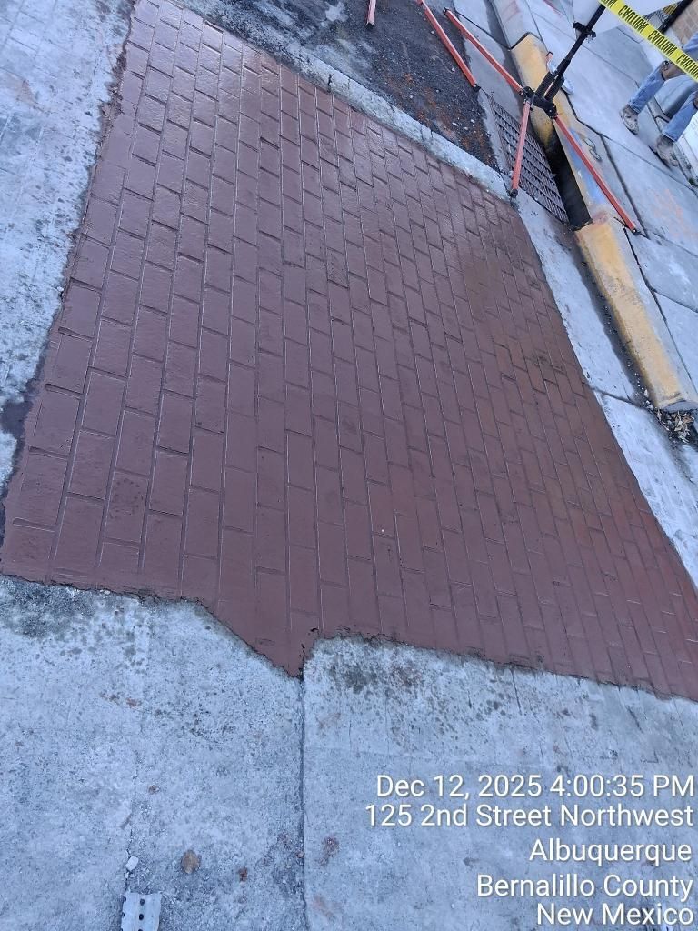Brick sidewalk ramp beside a curb and street, with snow along the edges.
