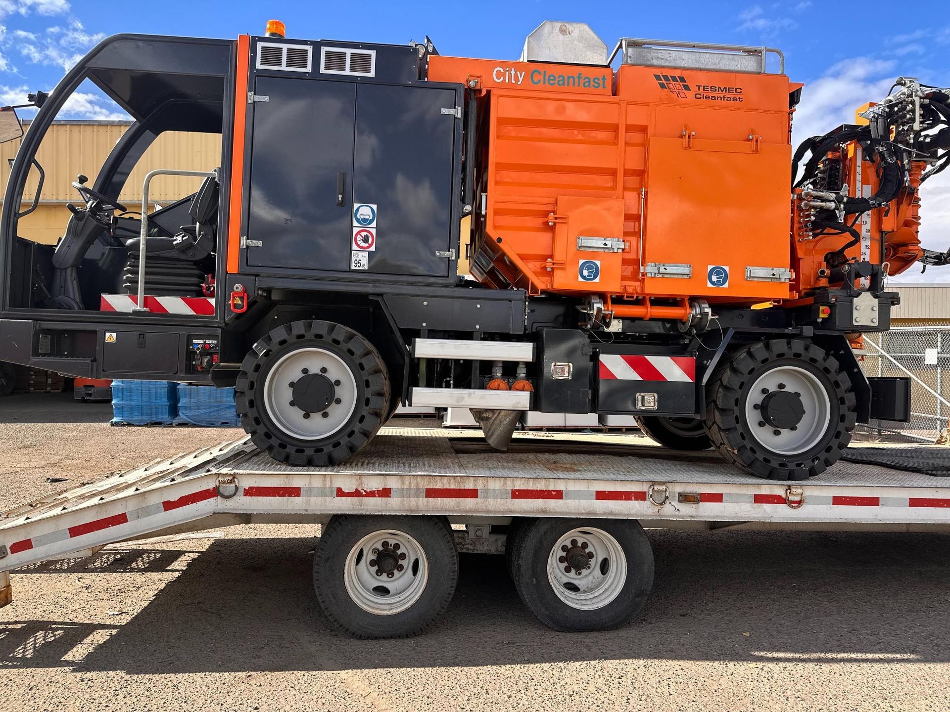 Orange industrial machine mounted on a trailer truck, side view outdoors.