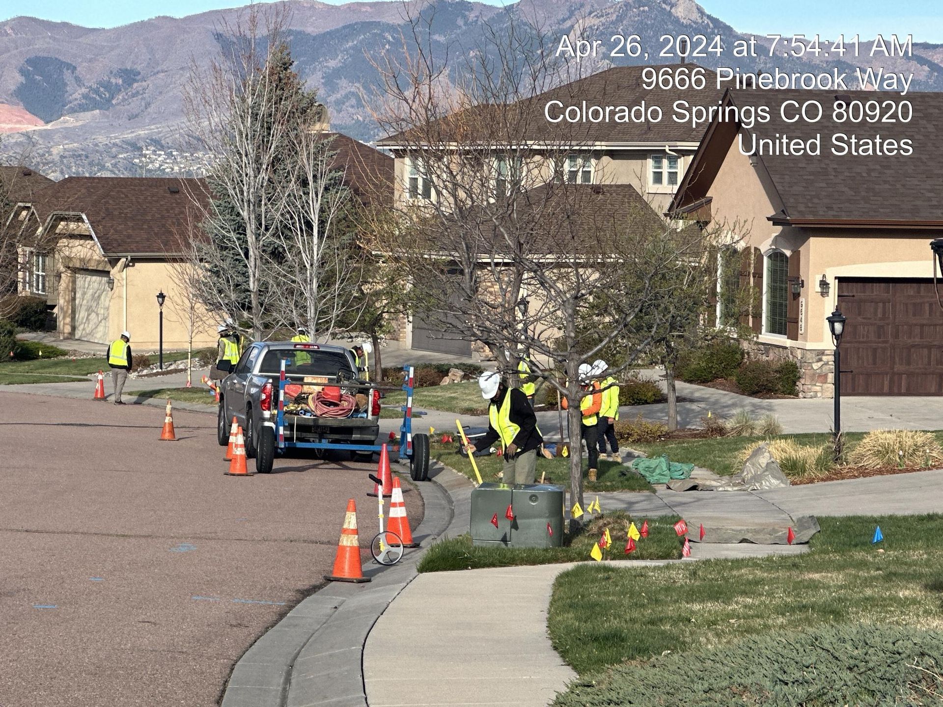 Utility crew working on roadside sewer repair with cones and truck in a suburban neighborhood