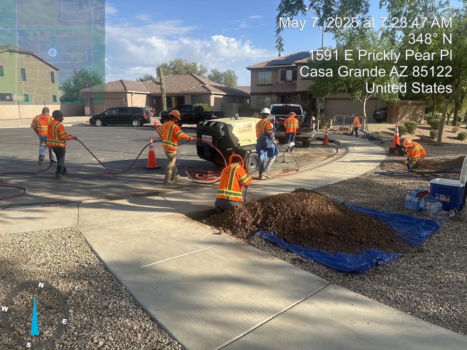 Workers in orange vests pour concrete for a curb ramp at a road construction site.