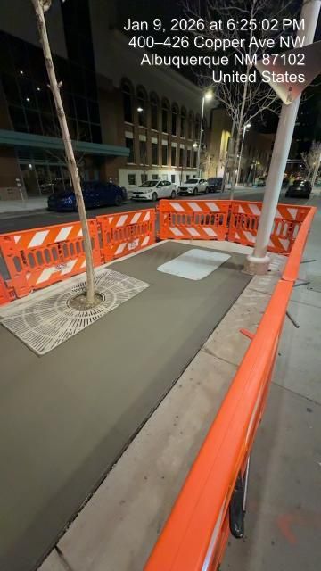 Orange construction barricades around a city sidewalk ramp at night on Copper Ave, Albuquerque