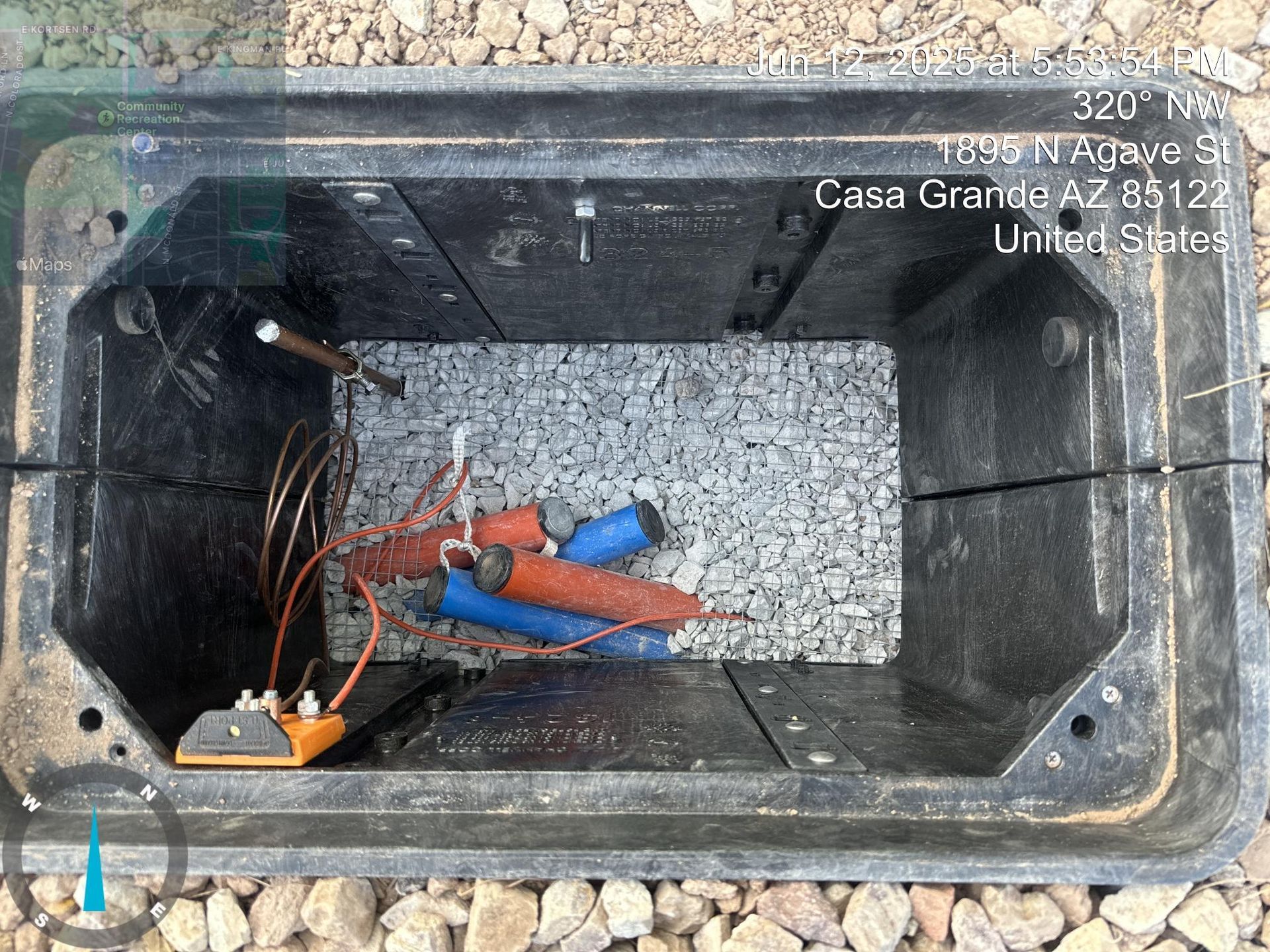 Open utility box with tangled wires and orange and blue connectors inside a dark compartment.