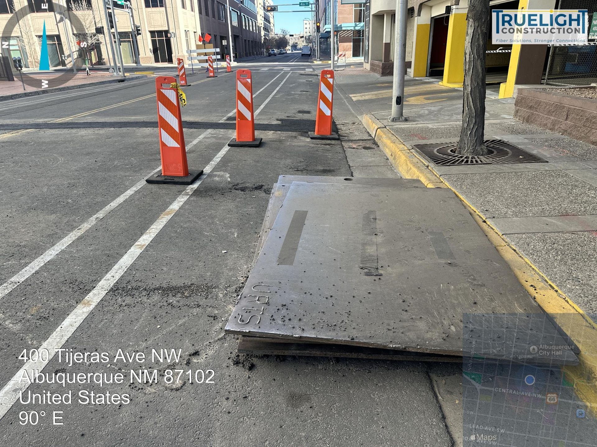 Damaged sidewalk ramp beside road, blocked by three orange safety cones and yellow curb