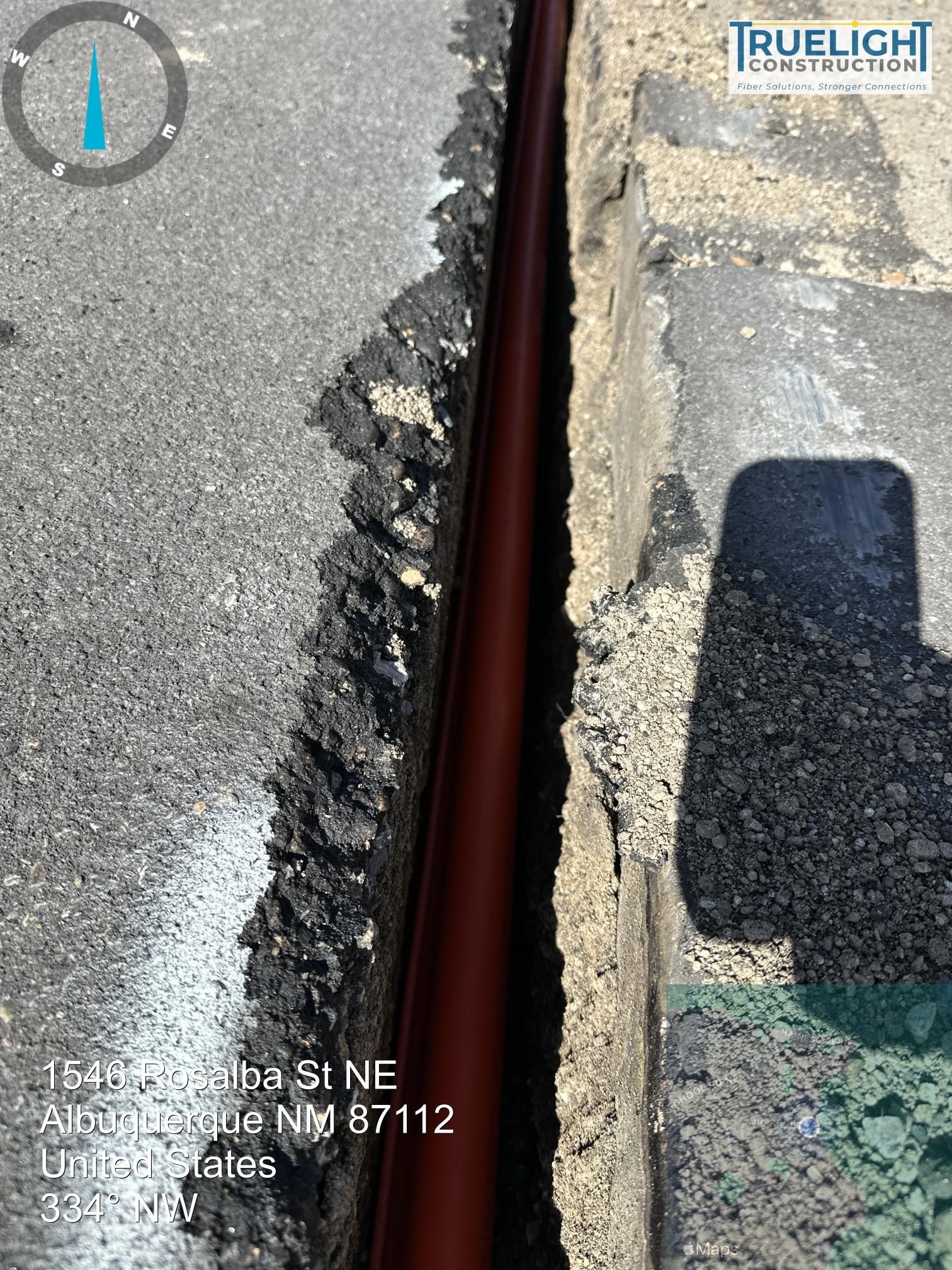 Cracked asphalt road with a long open seam exposing a dark gap between pavement sections
