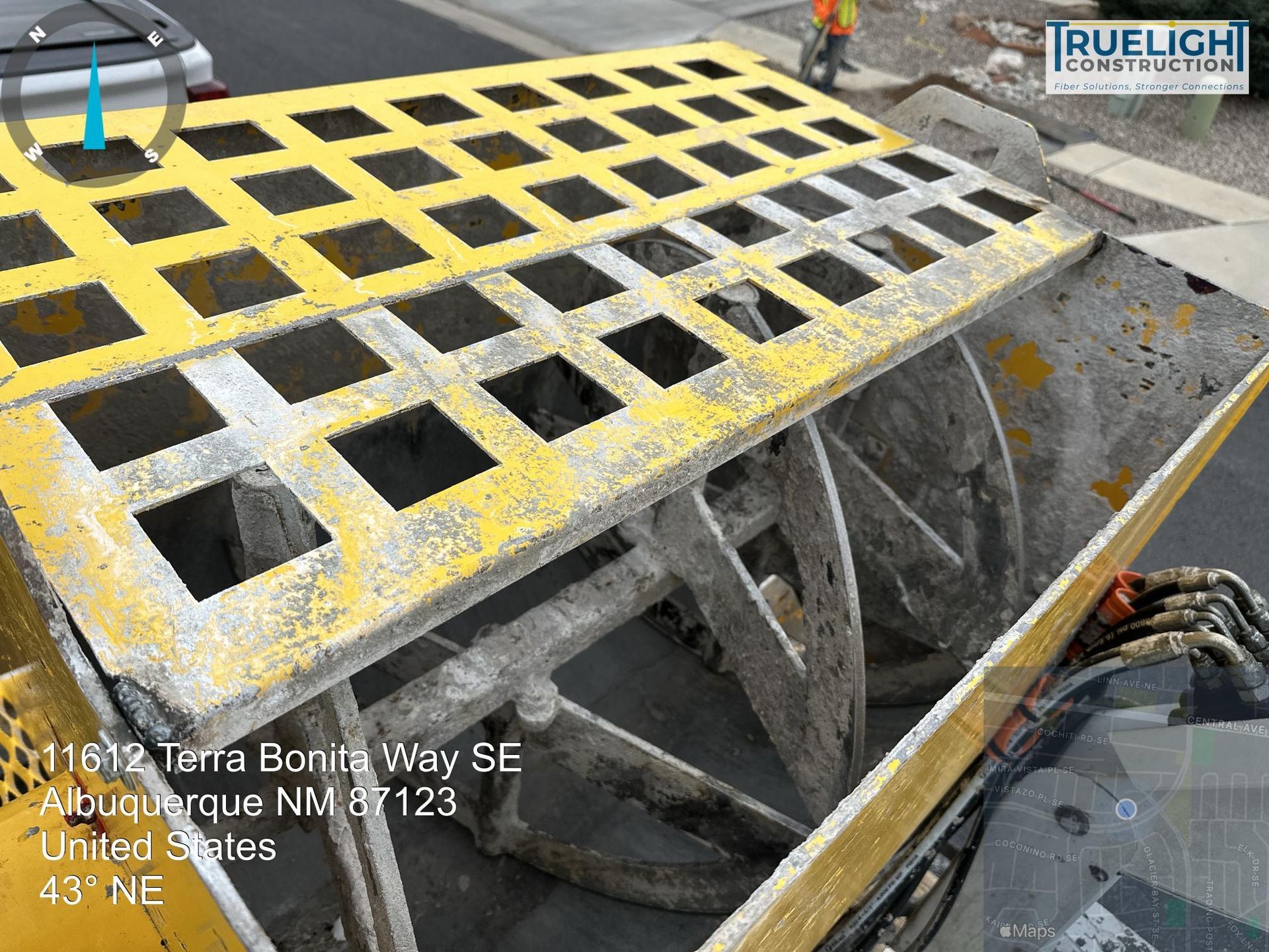 Yellow grated walkway over concrete chambers at a utility construction site, with pipes and equipment below