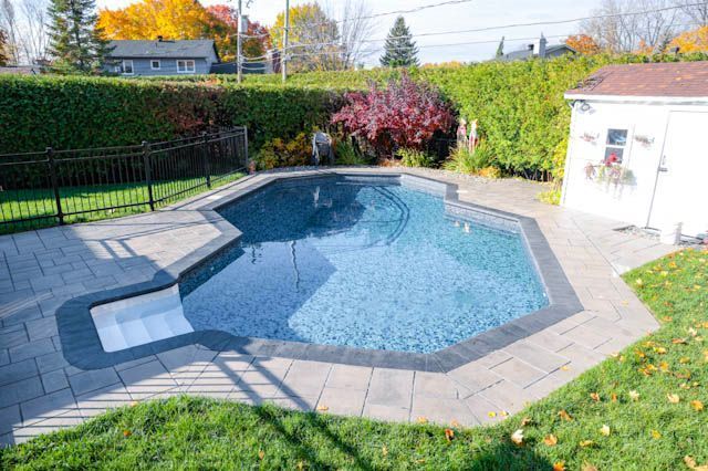 Piscine de jardin avec dalles grises, eau bleue et petit pool house blanc