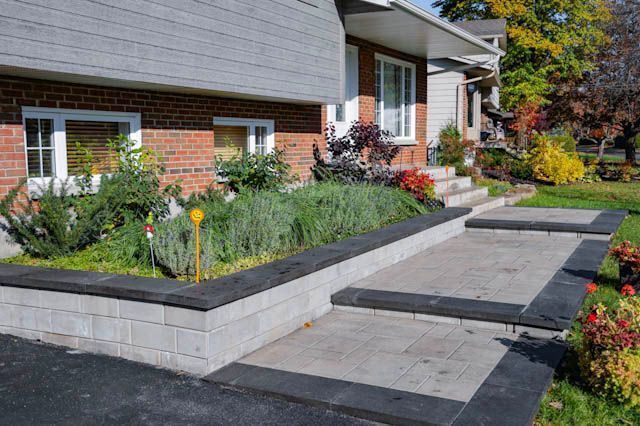 Cour avant d'une maison moderne avec jardinières surélevées en briques, allée en pierre et jardin paysager